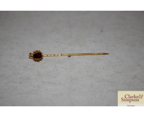 A yellow metal and red stone set stick pin