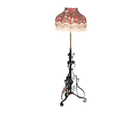 A LATE VICTORIAN IRON AND BRASS ADJUSTABLE STANDARD LAMP    IN THE MANNER OF W.A.S. BENSON, CIRCA 1900 With a shade decorated