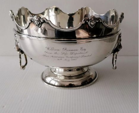 A George V silver monteith with shaped rim, carved mask decoration, moulded girdle, flanked by lion-mask drop-handles on a sp