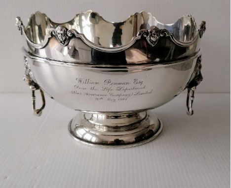 A George V silver monteith with shaped rim, carved mask decoration, moulded girdle, flanked by lion-mask drop-handles on a sp