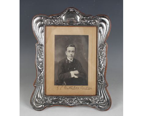 An Edwardian silver mounted shaped rectangular photograph frame, decorated in relief with foliate scrolls and presentation in