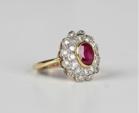 An 18ct gold, ruby and diamond cluster ring in a shaped oval design, claw set with the oval cut ruby within a two row surroun