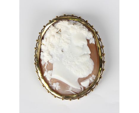 A gold mounted oval shell cameo brooch, carved as a portrait of Bacchus with wine cup and lyre motifs, the later mount with a