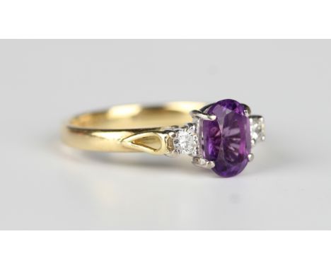 An 18ct gold ring, claw set with an oval cut amethyst between two circular cut diamonds, London 1990, weight 2.7g, ring size 