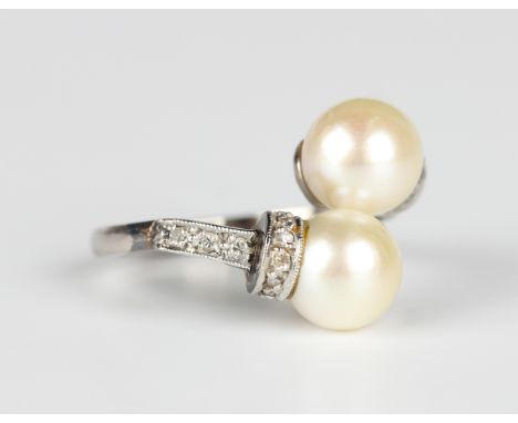 A white gold, platinum, cultured pearl and diamond ring in a twistover design, mounted with two cultured pearls and cushion c