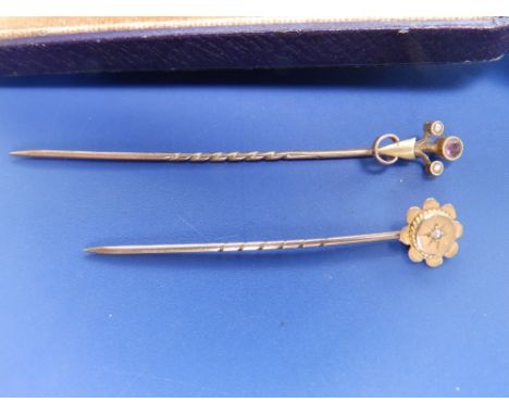 A 9ct stick pin set with a small diamond and one other. (2)