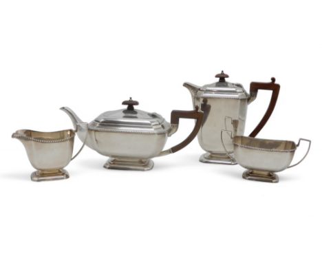 A GEORGE V FOUR PIECE SILVER TEA SERVICE by Henry Clifford Davis, Birmingham 1932, of faceted form, with wooden handles and f