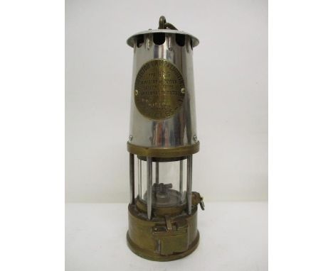 A Protector Lamp & Lighting Co Ltd type GRG brass and polished metal minors safety lamp with a clear glass panel and name pla