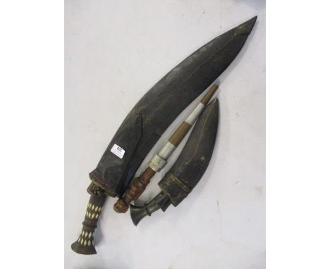 An early 20th century Kukri knife and a smaller example, together with a tribal carved knife and scabbard 