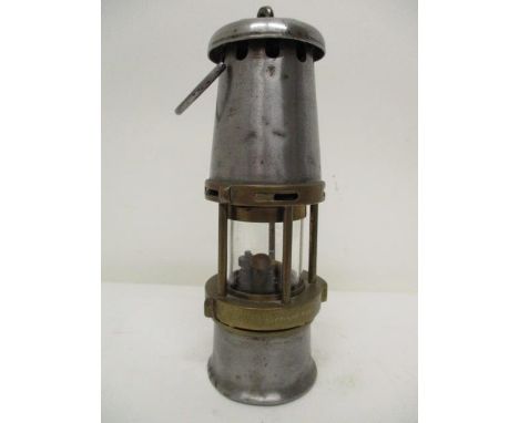 A small Wolf Safety Lamp Co brass and polished metal miners safety lamp with a clear glass panel and plate to the top, stampe