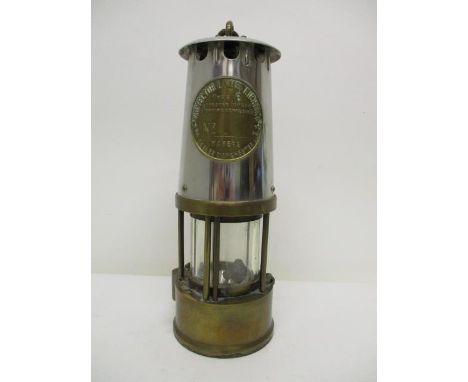 A Protector Lamp & Lighting Co Ltd type 6 brass and polished metal miners safety lamp with a clear glass panel and name plate