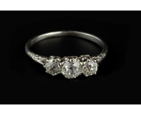 A DIAMOND THREE STONE RING, the graduated old-cut diamonds in claw setting, between scroll carved shoulders, white precious m