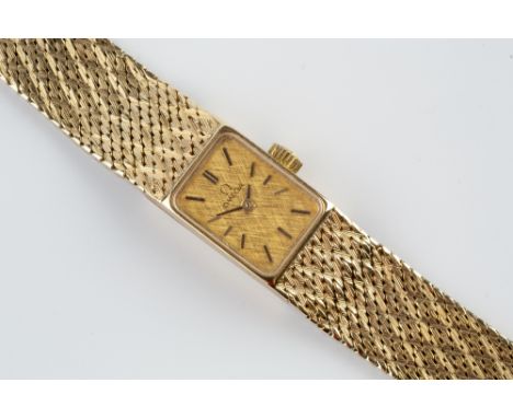 A LADY'S 9CT GOLD BRACELET WATCH BY OMEGA, the rectangular textured gilt dial with baton markers, to a jewelled manual moveme