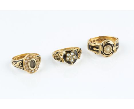 THREE VICTORIAN ENAMEL AND HALF PEARL MEMORIAL RINGS, the first centred with a heart-shaped hinged locket compartment, applie