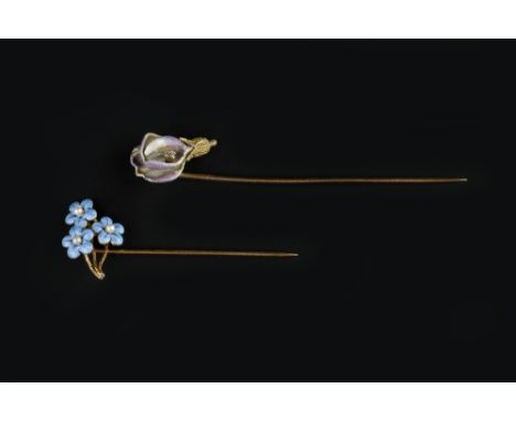 TWO ENAMEL AND GEM SET STICK PINS, the first modelled as a flowerhead heightened with lilac and white enamel petals, with an 