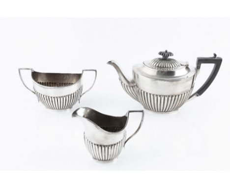 A SILVER THREE PIECE TEA SERVICE of half lobed form, the teapot with ebonised handle and knop, by James Deakin &amp; Sons, Sh