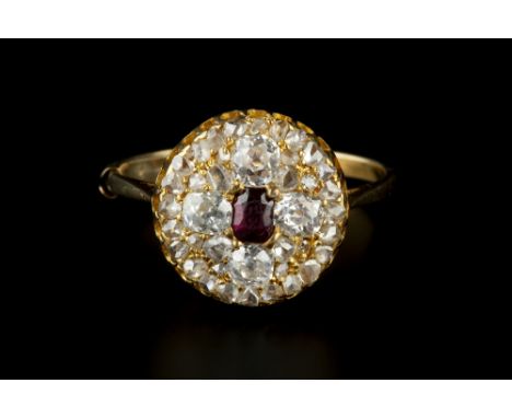 A RUBY AND DIAMOND PANEL RING, the circular panel centred with a cushion-shaped mixed-cut ruby, bordered by four cushion-shap