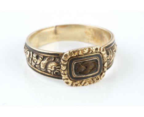 A GEORGIAN MEMORIAL RING, the cushion-shaped panel centred with plaited hairwork, framed by black enamel and carved flowerhea
