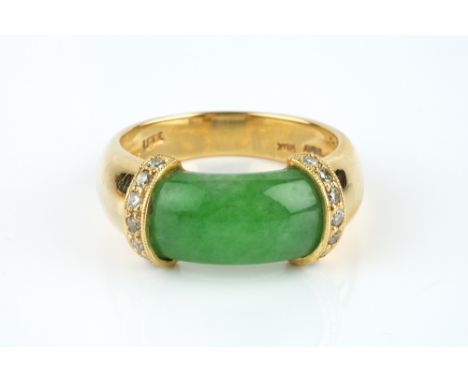 A JADE AND DIAMOND DRESS RING, the shaped jade cabochon bordered by collars of round brilliant-cut diamonds, yellow precious 