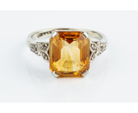 A CITRINE AND DIAMOND DRESS RING, the rectangular step-cut citrine with canted corners, claw set between foliate shoulders of