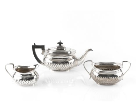 AN EDWARDIAN SILVER THREE PIECE TEA SERVICE, of half lobed design, the teapot with ebonised handle and knop, by Henry Matthew