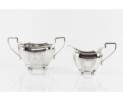 AN EDWARDIAN SILVER TWIN HANDLED SUGAR BASIN, and matching milk jug, of shaped outline, engraved with trailing foliage on bun