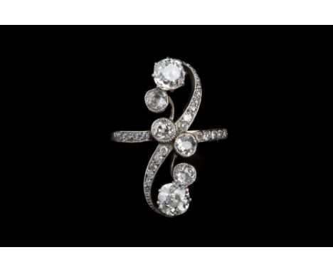 AN EARLY 20TH CENTURY DIAMOND PANEL RING, the scrolling openwork panel of graduated cushion-shaped and old-cut diamonds in cl