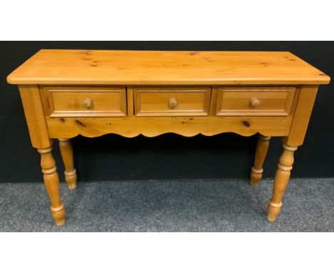 A pine console table, over sailing top, three frieze drawers, shaped apron, turned legs, 78cm high, 122cm wide, 41.5cm deep 