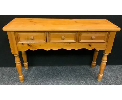 A pine console table, over sailing top, three frieze drawers, shaped apron, turned legs, 78cm high, 122cm wide, 41.5cm deep 