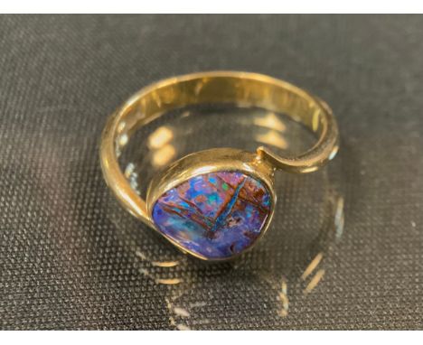 A black opal ring, free form deep opal, flashing violet, pinky red, blue and green, 18ct gold shank, size M/N, 3.5g gross 