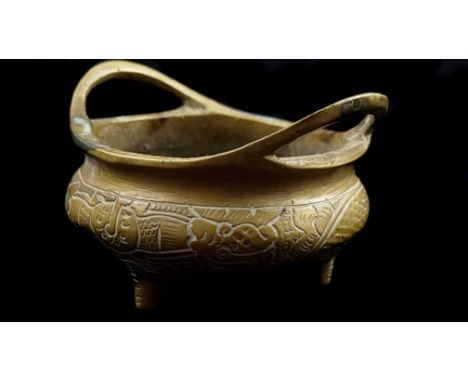 A small Chinese bronze censer, circular with two high loop handles and on tripod feet, the whole finely decorated with a scro