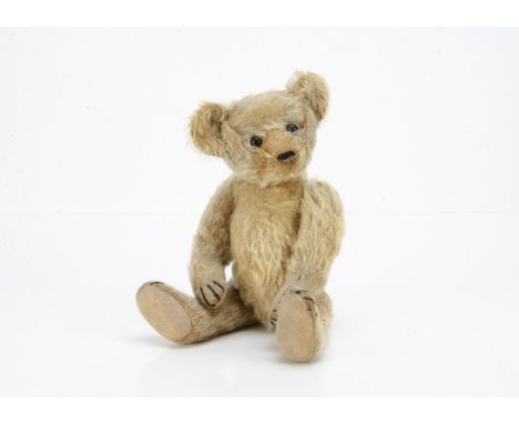 An early American teddy bear circa 1908, with blonde mohair, black boot button eyes, pronounced slightly upturned muzzle, bla