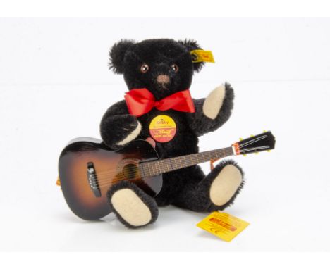 A Steiff yellow tagged Bobby Musical Teddy Bear, black with guitar, in original box, 1993 (slight damage to box)