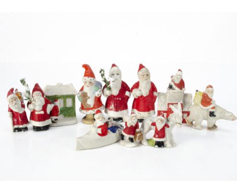 Eleven bisque Father Christmas cake decorations, including one riding a polar bear, looking in a house window, going down a c