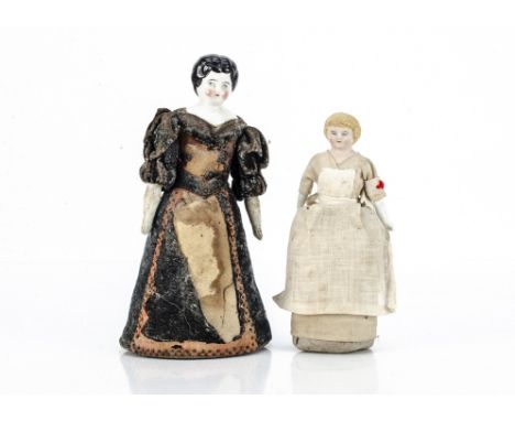 Two doll pin cushions, a bisque shoulder-head doll in nurses uniform --6 ½in. (16.5cm.) high; and a china shoulder-head doll 