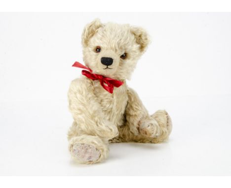 A post-war Chad Valley teddy bear, with blonde mohair, orange and black glass eyes, clipped muzzle, black stitched nose and m