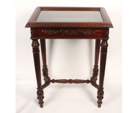 A reproduction mahogany finish table vitrine, hinged glazed panel, over a carved frieze on turned and carved legs