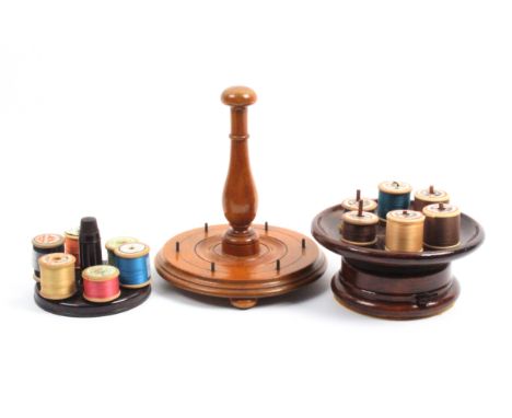 A mixed lot – sewing – comprising two wooden circular reel stands, another in plastic with central needle holder and thimble,