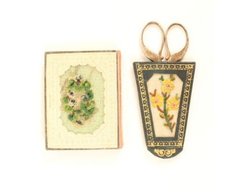 A pincushion book and a scissor case, the pincushion book with a petit point canvas panel of flowers to one side and a bird o