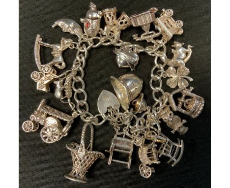 A silver charm bracelet, suspending twenty one charms inc Owl, Firemans Helmets, Pram, Rocking Chair, Traction Engine etc, 82