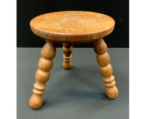 A Hunstone hand carved light oak stool, carved seat, turned tripod legs, 26cm high, 25cm diameter 