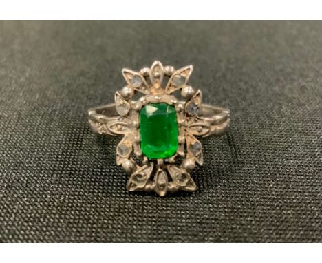 An Art Deco diamond and emerald dress ring, central rectangular cushion cut emerald (treated) within rose cut diamond accente