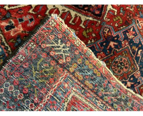 An Antique, hand-knotted, Persian Heriz rug / carpet, with stylised motifs in shades of pale blue, deep indigo, and red, 186c