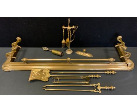 A late 19th century scroll end brass fender;  companion set on stand;  iron rest;  oak fire screen etc 