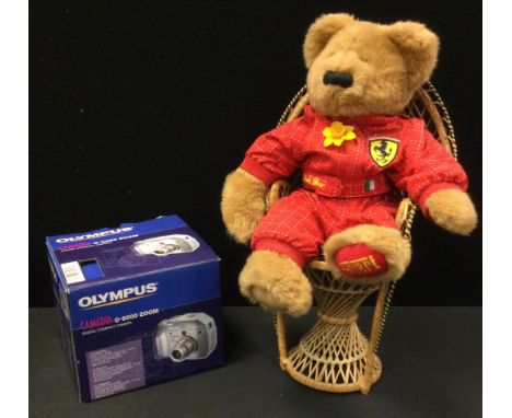 A Ferrari bear, on a wicker peacock chair;  an Olypis G5000 Zoom camera 