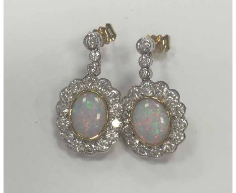 PAIR OF OPAL AND DIAMOND CLUSTER EARRINGS each set with a central oval cabochon opal measuring 9.5 x 7.2mm surrounded by bril
