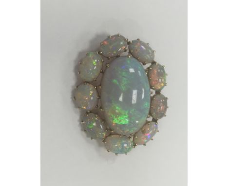 OPAL BROOCH
with a large central oval cabochon opal measuring 21.4 x 13.5mm, surrounded by smaller oval cabochon opals, in ni
