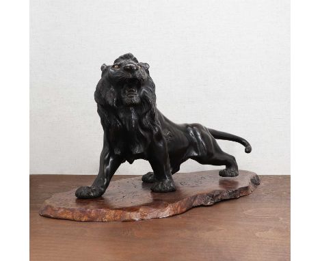A Japanese bronze okimono,Meiji period (1868-1912), of a lion, naturalistically modelled, striding forward with its long tail