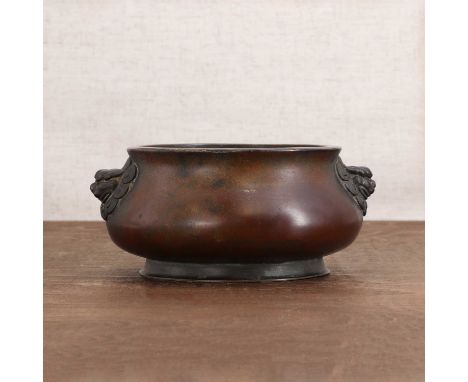 A Chinese bronze incense burner,the compressed globular body rising from a flared foot flanked by two Buddhist lion handles, 