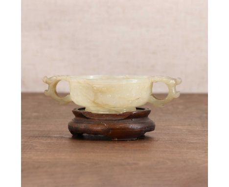 A Chinese jade cup,Ming dynasty (1368-1644), the rounded sides rising from a splayed circular foot, flanked by two dragon-hea